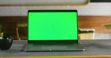 open laptop with a green screen stands on a table in coffee shop open laptop with a green screen stands on a table in a coffee shop, close-up. There are no people in the frame. Chrome key, copy space video