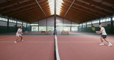 Young tennis players play tennis with each other, throwing the ball over the net with a racket. Long throwing the ball over the net, playing on a steep tennis court video