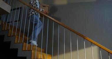 The young family moves to a new home, lots of boxes and things are placed everywhere. A man and a woman are contentedly sitting on the couch and looking at the phone, resting after collecting things video