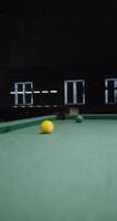 A white billiard ball hits another ball and it bounces off the hole without hitting it, close-up. No people in the , only a pool table, vertical video