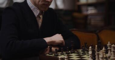 A European-looking man wearing a business suit thinks intently while looking at the chessboard before making a move video