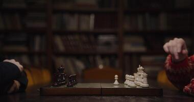 A man and a woman start a chess game, sitting opposite each other at a table in the library, close-up of a chessboard video