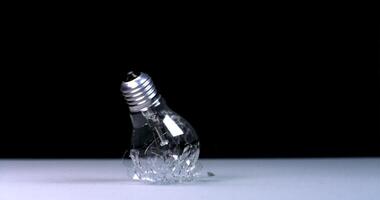 A light bulb falls and breaks, slow motion against a black background, flying debris video