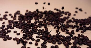 Coffee beans fall on the table, bouncing and scattering in slow motion video