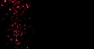shiny confetti in the form of stars falls and scatters against a black background, in slow motion video