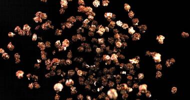 Caramel popcorn in bulk soars upward, whirling beautifully in slow motion and falls backwards against a black background video