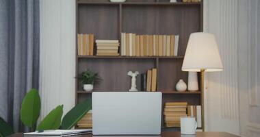 A beautifully furnished workplace with an open laptop, a mug and a notepad standing on the table in a modern stylish interior, without people video