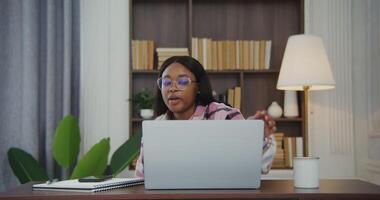 Beautiful african american woman opens the lid of a laptop and starts a serious conversation via a call. while sitting at a work table in a modern stylish interior video