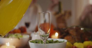 Shooting close-up, pouring juice from a decanter into a glass, standing on a richly set festive table. video