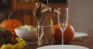 A festive richly set table with a bottle of wine and glasses, real pumpkins for decoration and a variety of different dishes. Close-up video