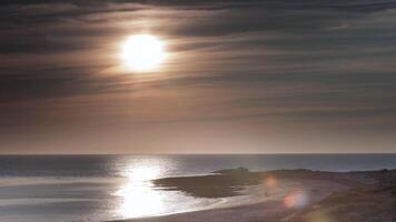 A beach with a large body of water and a lighthouse video