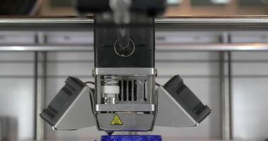 Front close up view of 3d printer in process It makes pieces for equipment with blue plastic video