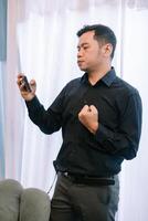 Determined man receiving good news on his phone while posing indoors photo