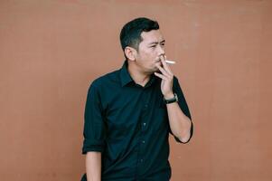 Contemplative man smoking a cigarette against a neutral backdrop photo