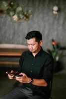 Absorbed man using cellphone indoors with muted background design photo