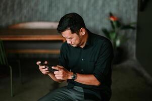 Engrossed man interacts with his mobile device at relaxing lounge setting photo