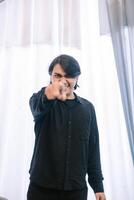 Expressive man pointing with intensity towards the camera with white curtain photo