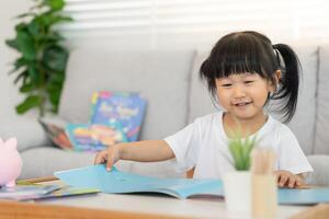 Happy Asian children relax read book at home. daughter and reading a story. learn development, childcare, laughing, education, storytelling, practice, imagine, reduce addiction mobile phone. photo