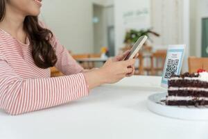 Woman use smartphone to scan QR code for order menu in cafe restaurant with a digital delivery. Choose menu and order accumulate discount. E wallet, technology, pay online, credit card, photo