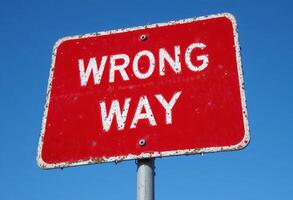 Wrong Way Traffic Sign Against Clear Blue Sky, Symbolizing Error or Misdirection, Mistake and Misstep photo