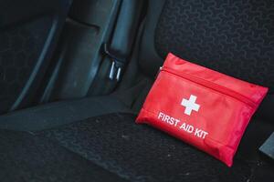 In the back seat of the car, there is a bright red colored first aid kit conveniently positioned and ready for any medical emergencies that may arise while traveling in the vehicle photo