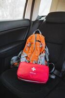 In the rear compartment of a vehicle, there is a backpack along with a first aid kit placed securely on the back seat to ensure easy access and safety for any potential emergencies photo