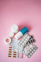 A colorful mix of pills, capsules, and medicine bottles is spread across a bright pink background, creating a striking, captivating contrast that grabs the viewers attention photo