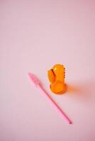 A soft pink surface serves as a delicate base for a vibrant pink brush beside a bright orange object, creating pleasing visual contrast and adding depth to the composition photo