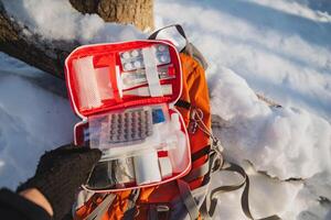 A person is standing in a serene snowy environment, holding a first aid kit, prepared to handle any emergencies that may arise amidst the white snow and picturesque winter scenery photo