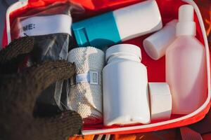 A person is carefully holding a bag filled with various bandages and bottles that are neatly organized inside a wellprepared first aid kit for emergencies or medical situations photo