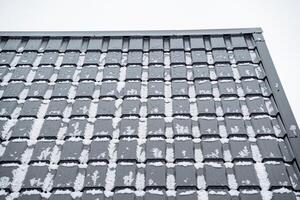 The image features a set of snowcovered roof tiles set against a tranquil winter sky background, bringing out the serenity and beauty of the cold snowy season photo