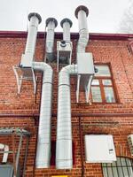 The structure in question is a brick building, notable for the presence of numerous pipes protruding from its exterior, showcasing an intricate plumbing system and utility infrastructure photo