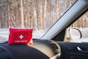 There is a bright red first aid kit that is placed on the dashboard of a car, easily visible and accessible in case of any emergencies. Safety is key, especially during winter photo