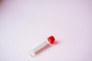 A strikingly bold redcapped test tube is placed elegantly upon a vibrant pink surface, resulting in a captivating and visually stimulating contrast within the laboratory setting photo