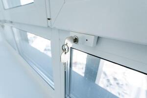 The image presents a closeup view of a window featuring a key inserted into the lock, hinting at various intriguing possibilities regarding entry points and overall security measures photo