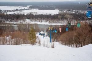 A charming chairlift in a winter landscape overlooks serene slopes and a calm river, creating an idyllic setting for fun activities and thrilling adventures with loved ones photo