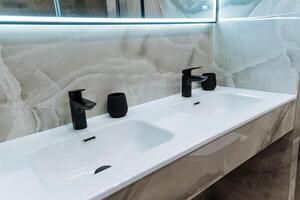 The bathroom features two elegantly designed sinks alongside a large mirror, providing functionality and style in one space. It serves as a practical area for daily routines photo