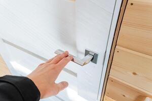 A person grips a pristine white door handle firmly with both hands, indicating a strong intention to enter or exit, marking a significant moment of transition in their journey photo
