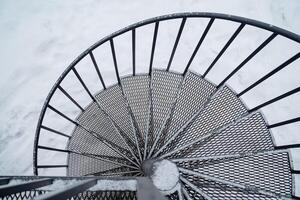 A detailed close up view of a beautifully designed metal spiral staircase surrounded by a blanket of pure white snow, creating a stunning contrast and scene of architectural elegance photo