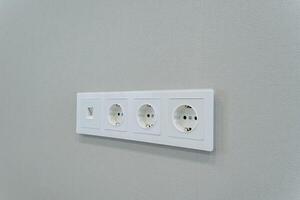 A white electrical outlet that is mounted on a gray wall is an essential component for connecting various devices to the common alternating current power supply in both homes and offices photo