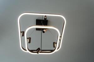 A stunning light fixture elegantly hanging from the ceiling, designed in an exquisite shape that resembles a clock, providing both illumination and a decorative touch to the space photo