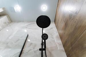 A highquality microphone is positioned on a sturdy stand in a beautifully designed bathroom, next to a mirror, enhancing its elegant presence and the overall aesthetics photo