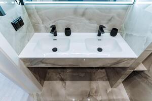In the bathroom area, there are two sinks conveniently located side by side, which are accompanied by a large mirror that beautifully reflects the overall design and style of the space photo