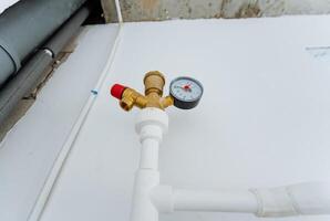 This image shows a detailed closeup view of a pipe which is equipped with a pressure gauge that is attached securely to it, indicating measurements for assessment purposes photo