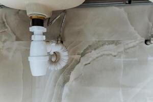 In a typical bathroom, there is a sink that features a drain pipe underneath it, essential for proper waste disposal and water drainage, contributing to the plumbing system of the house photo