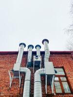 There is a brick building that has numerous pipes protruding from it, showcasing a complex network of plumbing and other utilities attached to its structure, enhancing its functionality photo