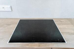 On a wooden counter, there is a black stove top oven that is prominently displayed. Its sleek design contrasts with the warm, natural wood, creating a stylish kitchen centerpiece photo