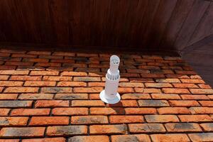 A white pipe is placed on top of a sturdy brick wall, which is composed of assorted bricks and mortar forming the structure, showcasing the craftsmanship in building materials used photo