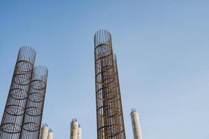 A large collection of sturdy metal pipes stands against a vibrant blue sky, showcasing an intricate display of engineering and industrial design in a highrise environment photo