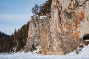 In the center of a snowy forest, there exists a large and impressive rock formation that stands out amidst the winter scenery, showcasing its geological significance and beauty photo